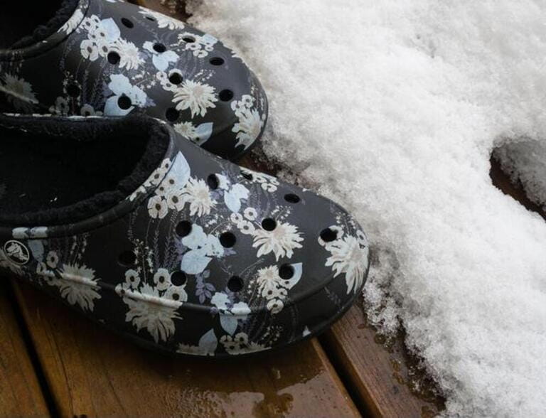 Pair of lined printed crocs on wooden deck covered with snow