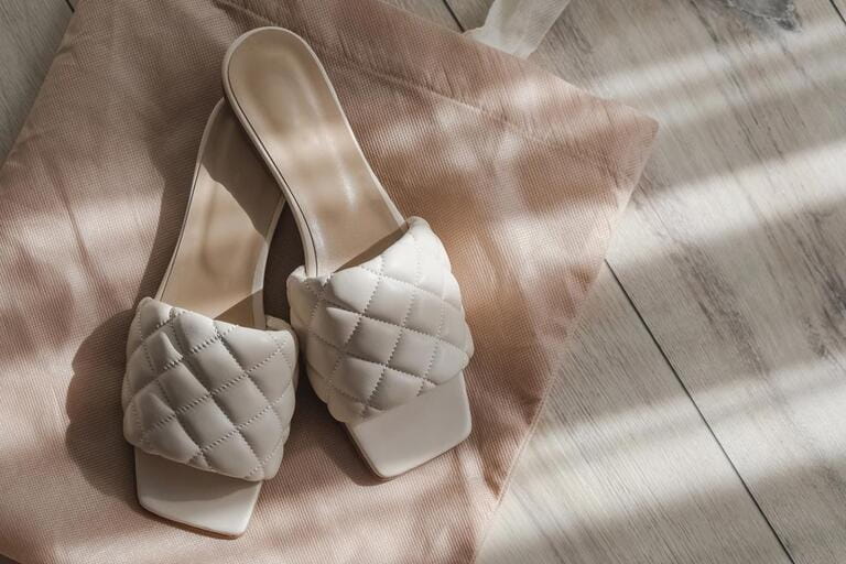 Modern feminine summer sandals, flops of beige color on the floor with natural morning sunlight Modern feminine summer sandals, flops of beige color on the floor with natural morning sunlight