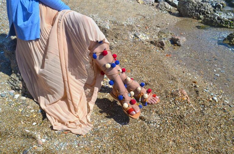 woman advertises traditional greek sandals gladiator on beach woman advertises traditional greek sandals gladiator on beach