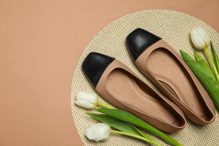 Pair of new stylish square toe ballet flats and beautiful tulips on beige background, flat lay. Pair of new stylish square toe ballet flats and beautiful tulips on beige background, flat lay.