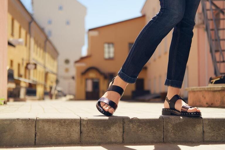 Female legs in sandals descending the stairs in the city