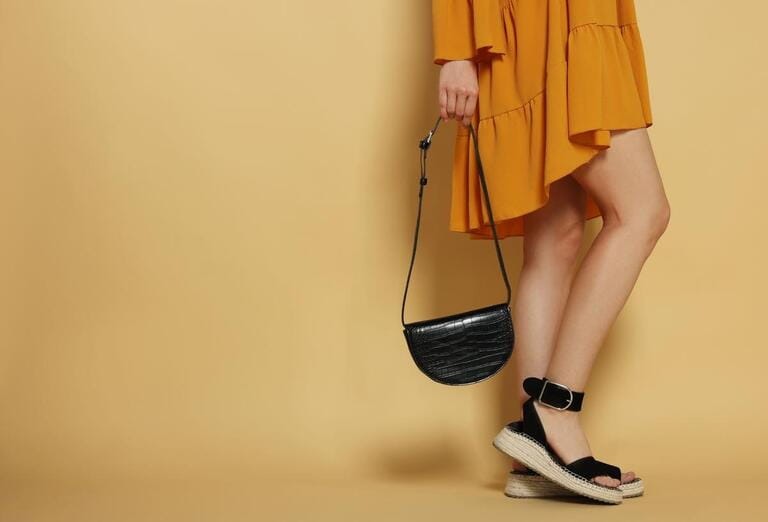 Woman with stylish bag on beige background, closeup. Space for text Woman with stylish bag on beige background, closeup. Space for text