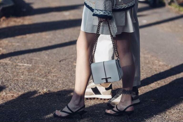 crop woman in knitted sweater skirt and sandals with chain bag standing near man wearing white pants and sneakers crop woman in knitted sweater skirt and sandals with chain bag standing near man wearing white pants and sneakers